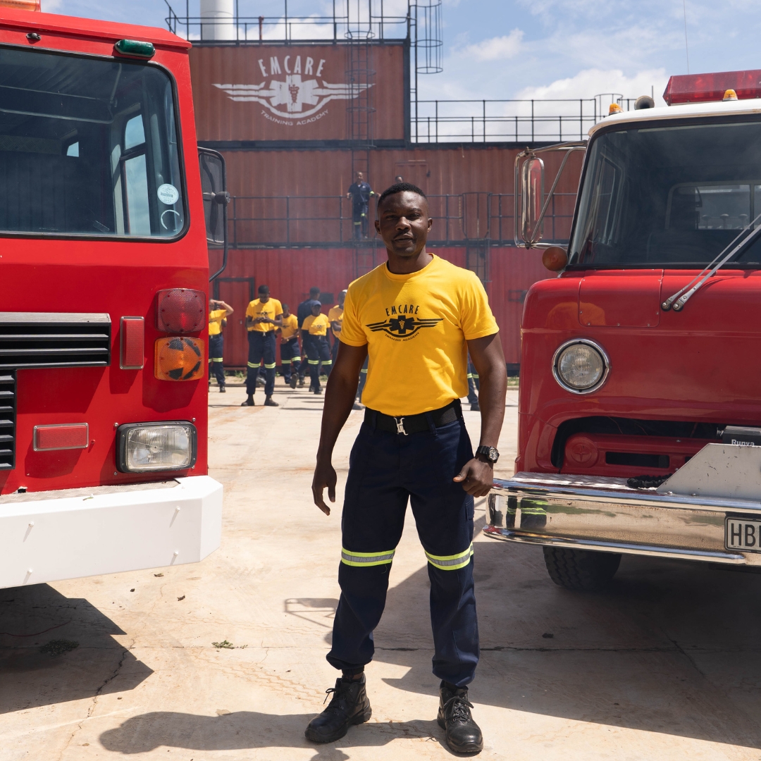 Male firefighter standing next to fire trucks